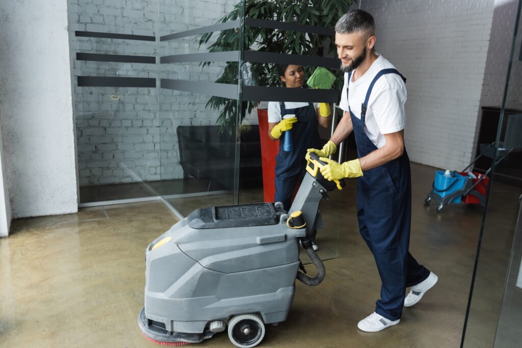 Bearded,Man,With,Floor,Scrubber,Machine,Near,Mixed,Race,Woman